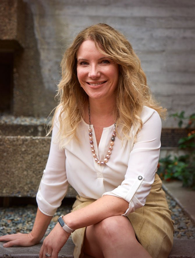 Headshot of Helena, where she is smiling and has wavy textured shoulder length blond hair, a pearl necklace, and white sweater